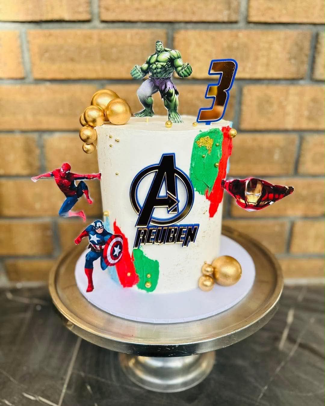 White Avengers birthday cake for Reuben's 3rd with Hulk on top, Spiderman, Iron Man and Captain America figurines and colourful brushstroke detail