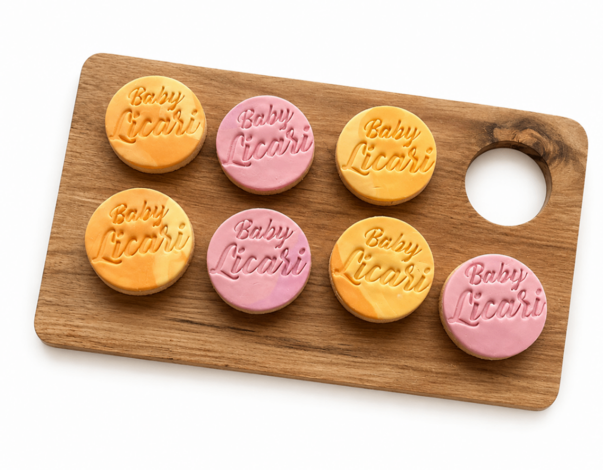 Orange and pink round stamped Baby Licari cookies on a wooden board