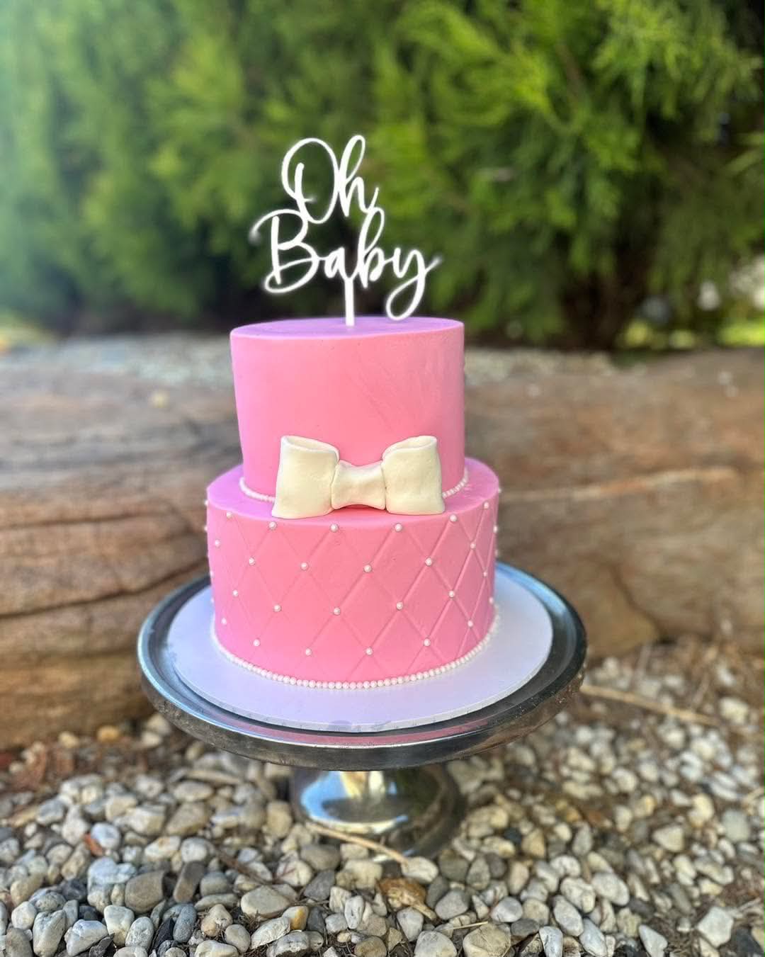 Two-tier pink quilted fondant baby shower cake with cream bow and Oh Baby acrylic topper