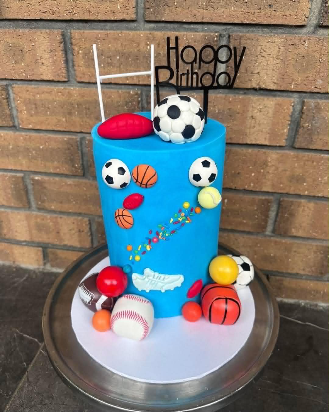 Blue fondant sports birthday cake with fondant soccer balls, basketballs, footballs, tennis balls and rugby posts