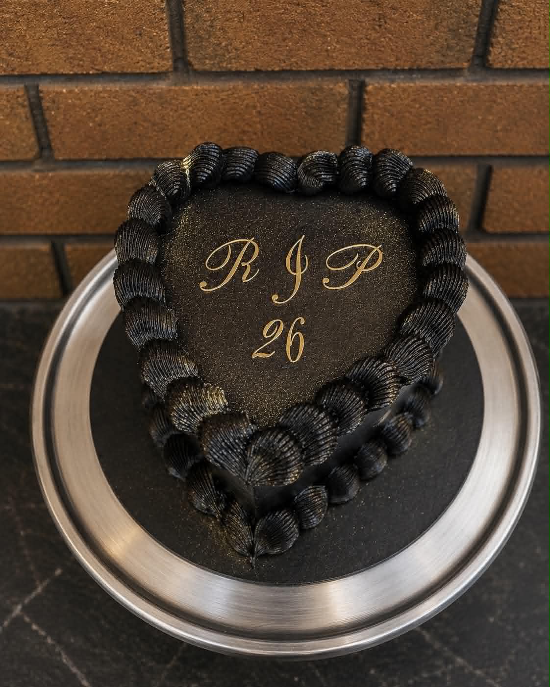 Black heart cake with gold script reading RIP 26 and black shell buttercream piping