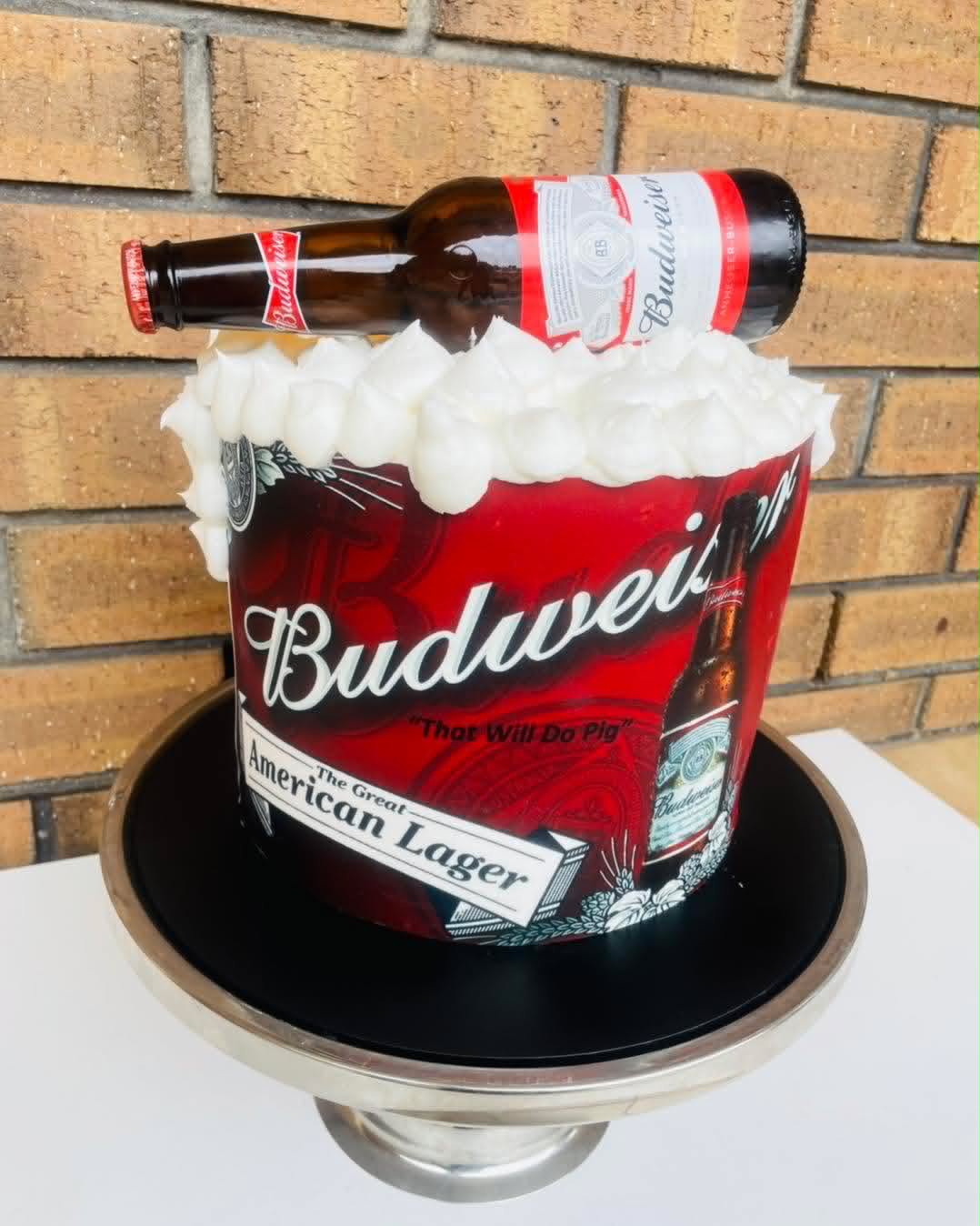 Round Budweiser beer can cake with white buttercream foam top, red Budweiser edible wrap and a fondant Budweiser bottle leaning on top