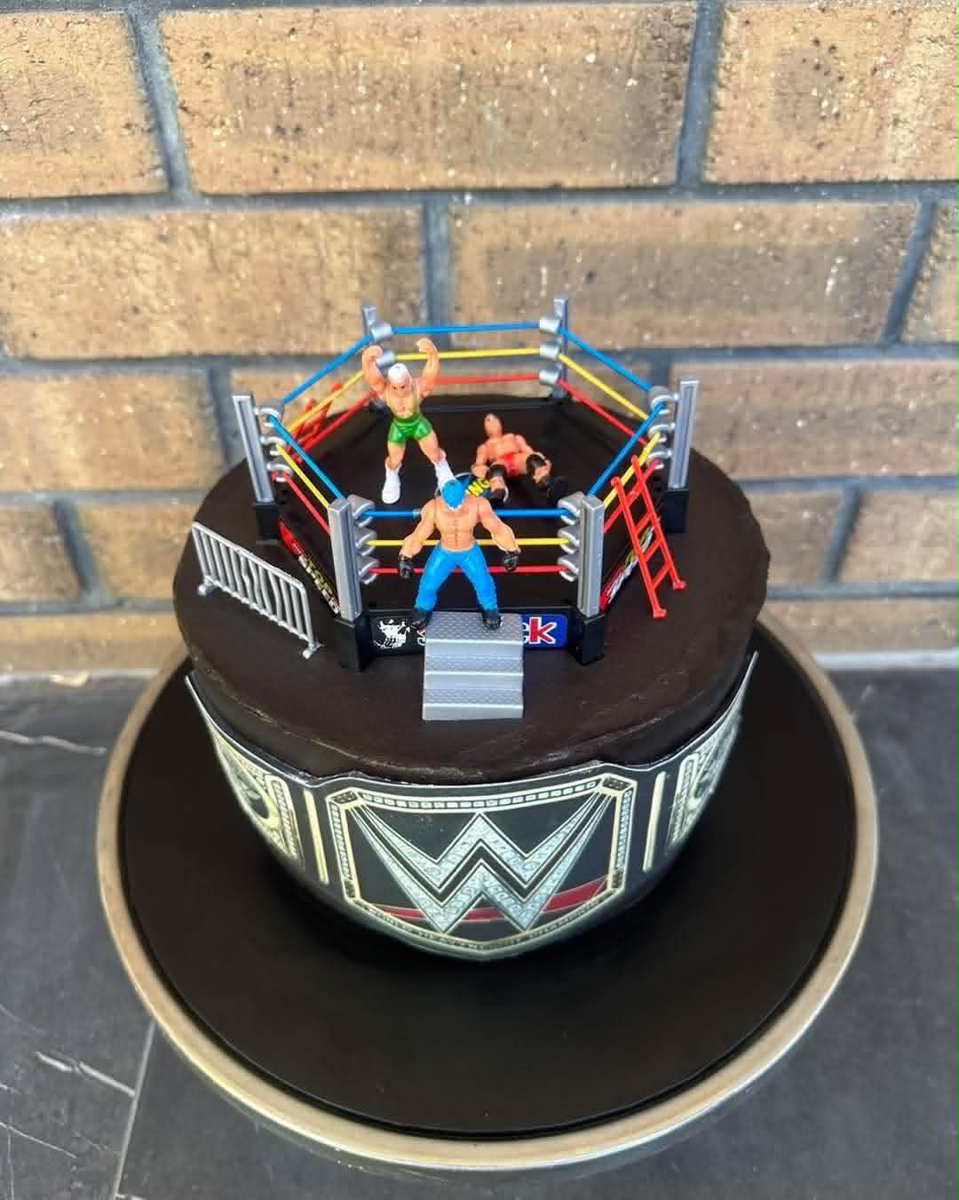 Dark chocolate WWE wrestling ring birthday cake with championship belt edible wrap, wrestling ring topper and three wrestler figurines