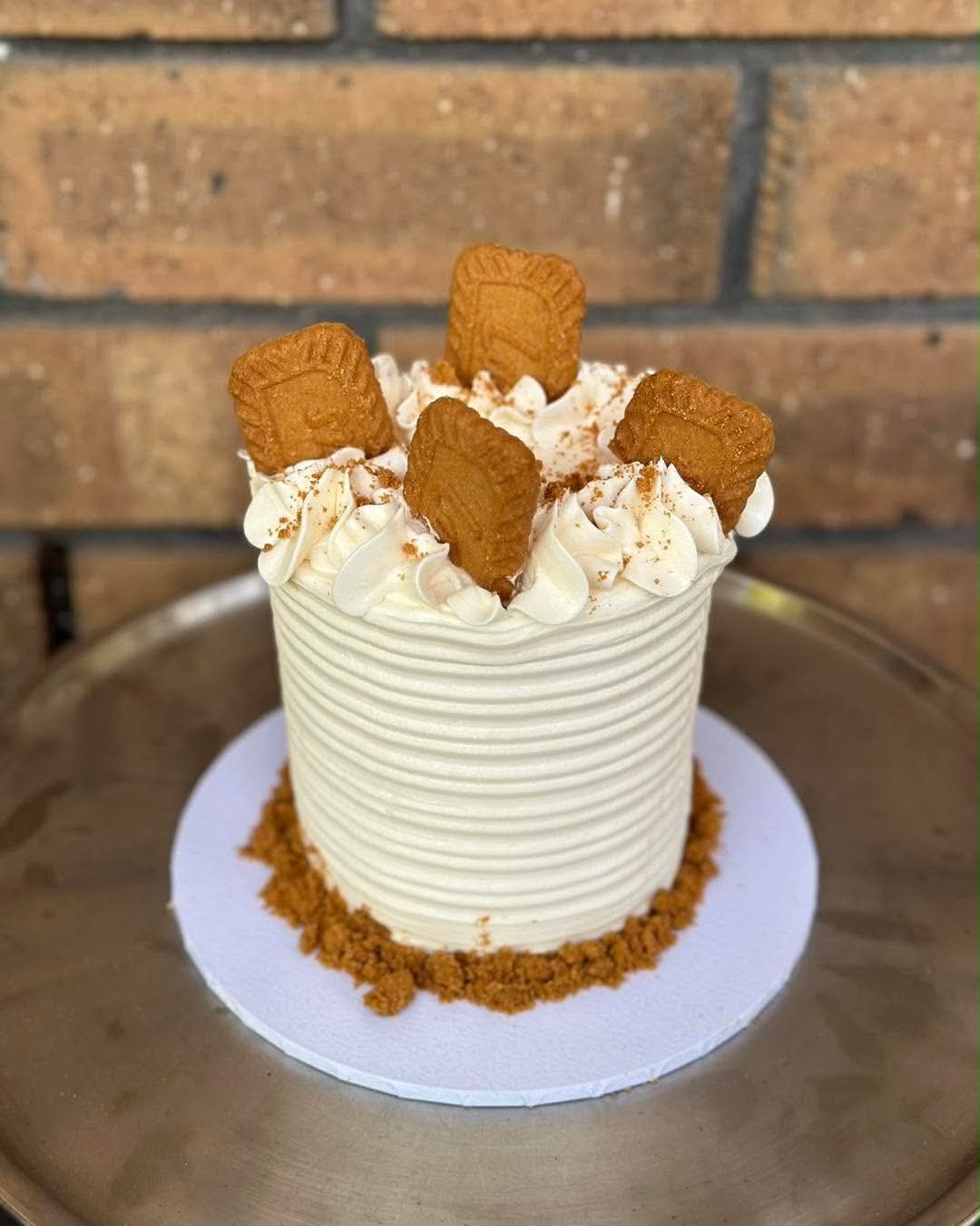 White Biscoff cake with ribbed buttercream sides, Biscoff crumb base, cream rosette top and Lotus Biscoff biscuits standing upright