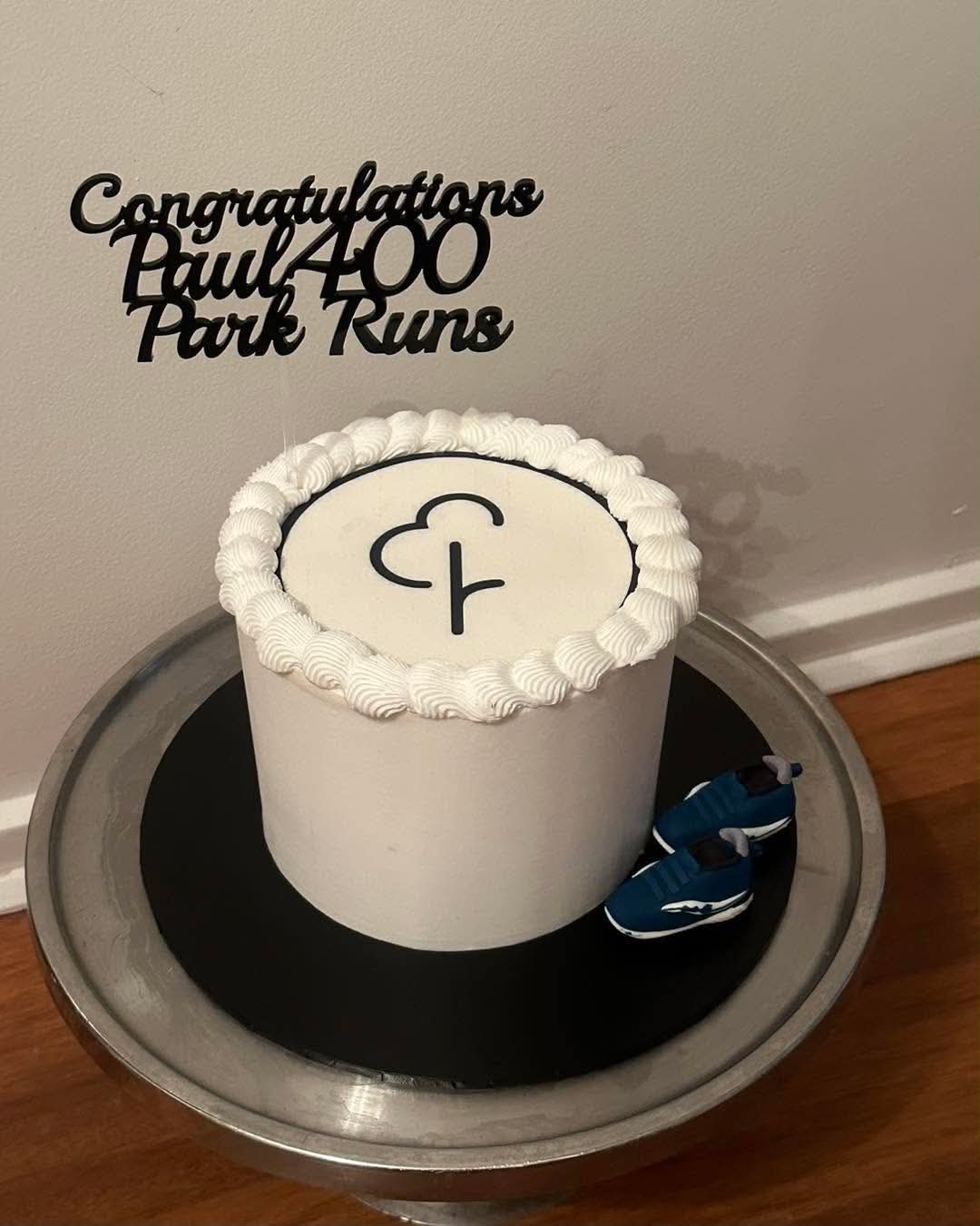 White Park Run birthday cake congratulating Paul on 400 park runs with Parkrun logo on top, shell piping border and blue running shoe topper