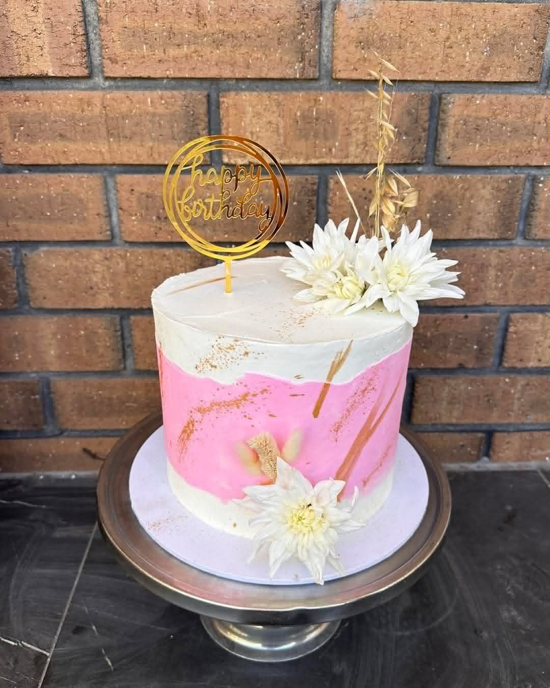 Lavender purple birthday cake covered in white fondant daisies and yellow fondant bumblebees on silver cake stand