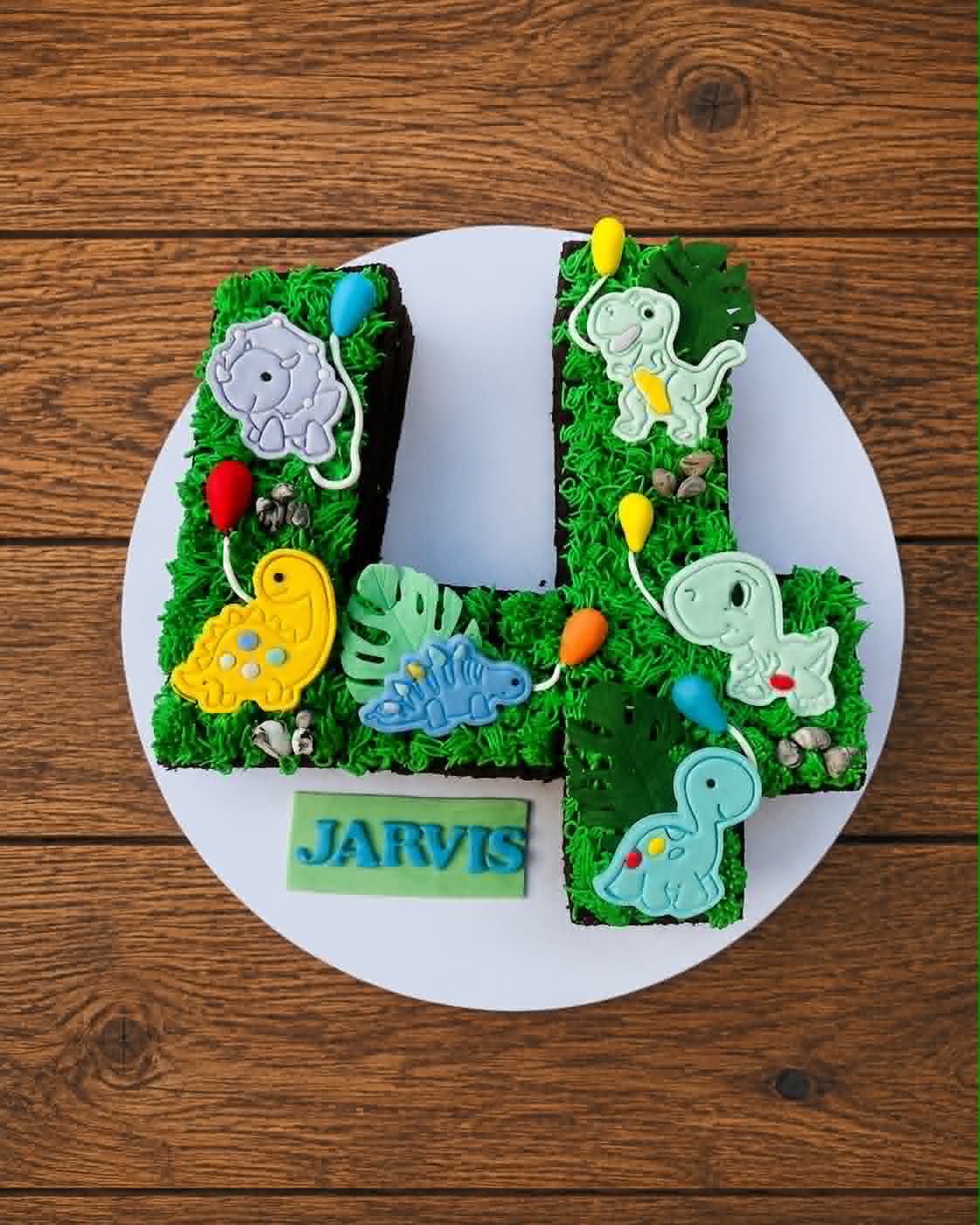 Number 4 shaped dinosaur birthday cake for Jarvis with green grass buttercream, fondant dinosaur toppers and colourful balloons