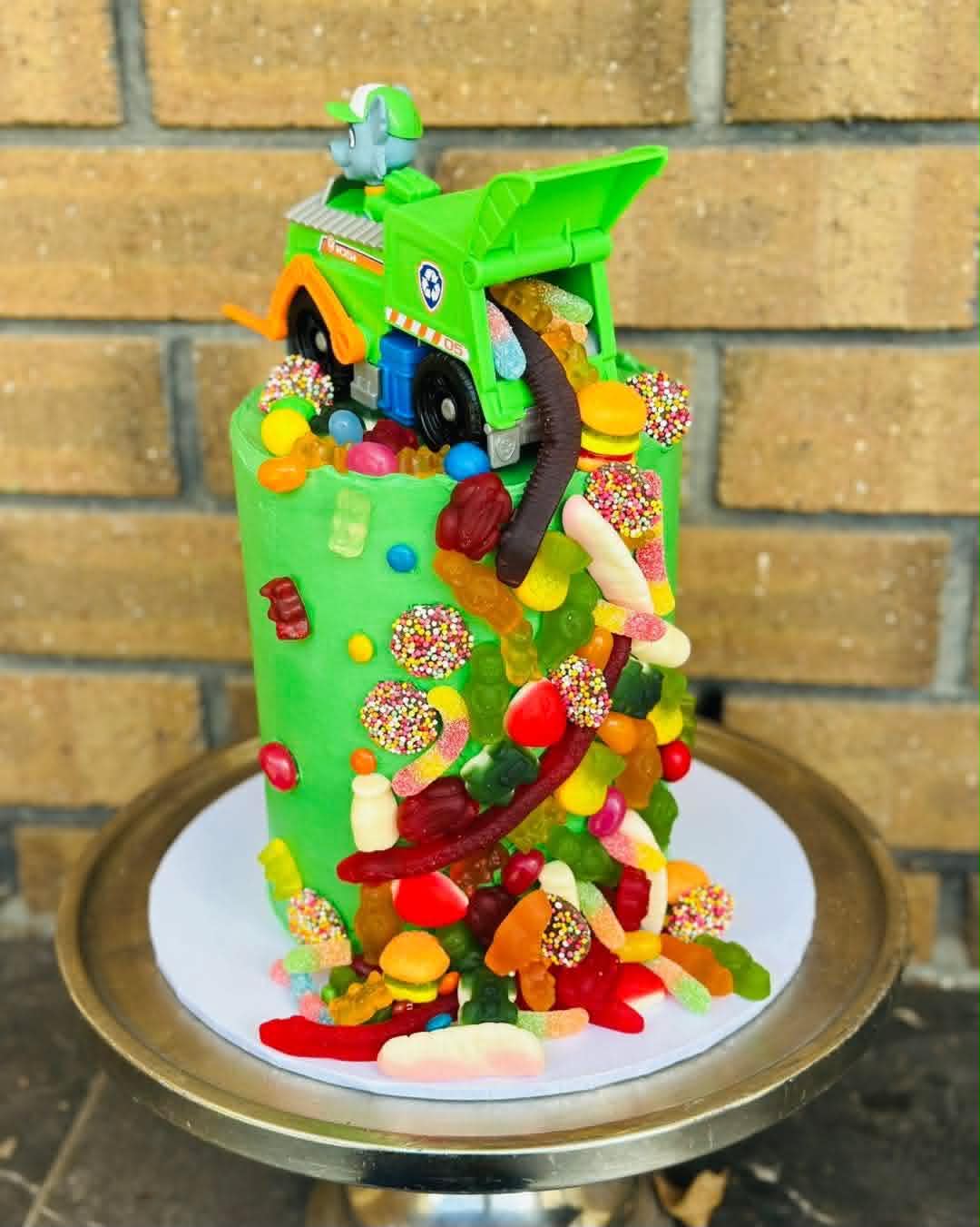 Green dinosaur birthday cake with fondant T-Rex and Brachiosaurus toppers, jungle leaves and Happy Birthday banner