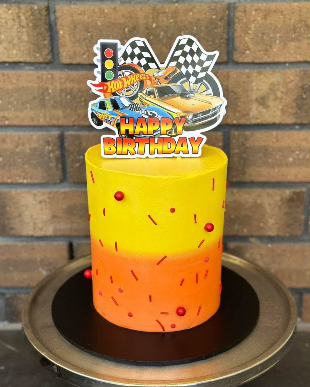 Yellow to orange ombre buttercream Hot Wheels birthday cake with red sprinkles and a Hot Wheels Happy Birthday acrylic topper
