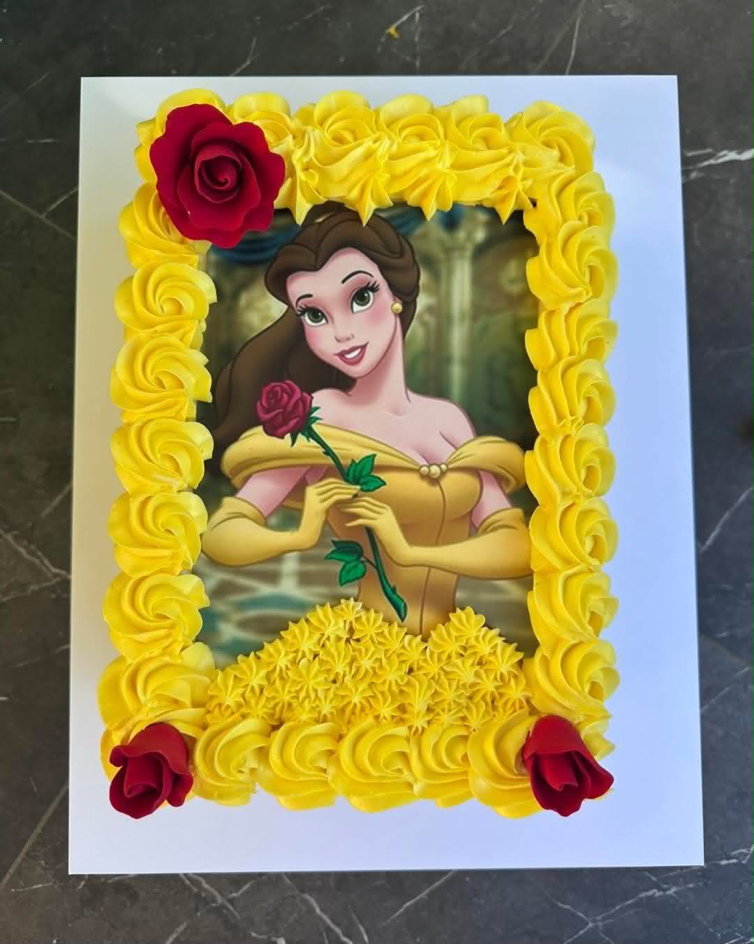 Yellow buttercream slab cake with Belle Beauty and the Beast edible print framed by yellow rosettes and red fondant roses