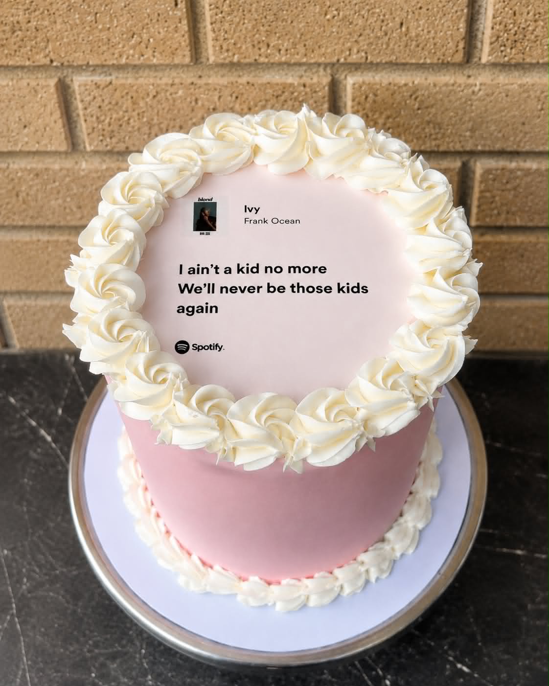 Pink buttercream vintage cake with ivory rosette border on top and Frank Ocean Ivy Spotify lyrics edible print reading I ain't a kid no more We'll never be those kids again